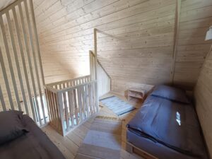 antresola z dwoma łóżkami, pojedynczym i podwójnym, małe dywany na środku