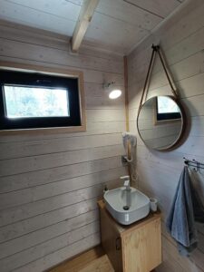 łazienka z małą umywalką i okrągłym lustrem